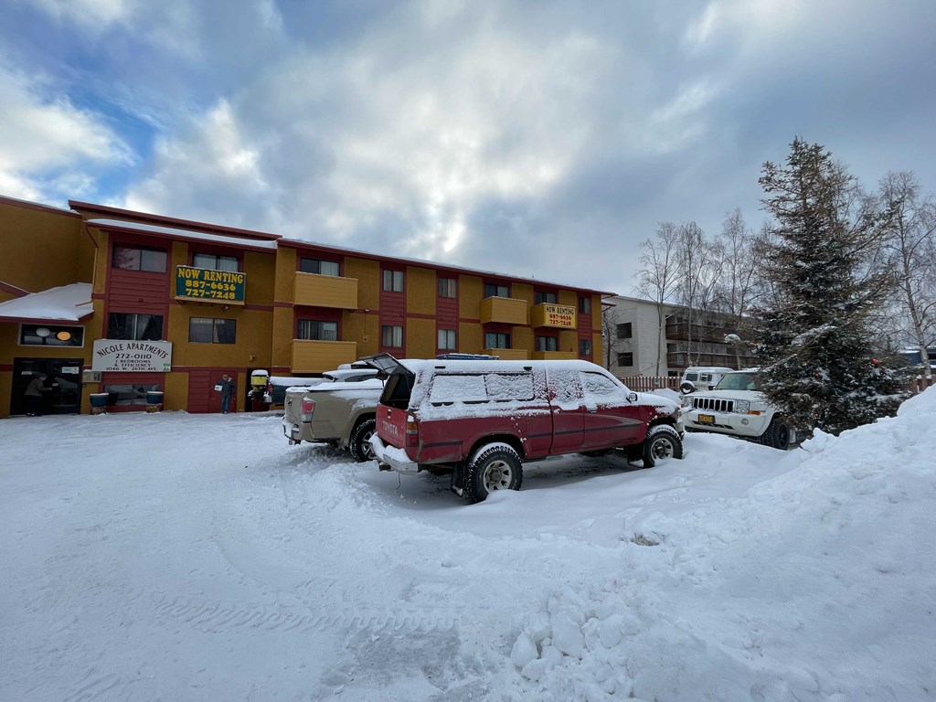 a red truck parked in the snow in front of a hotel
