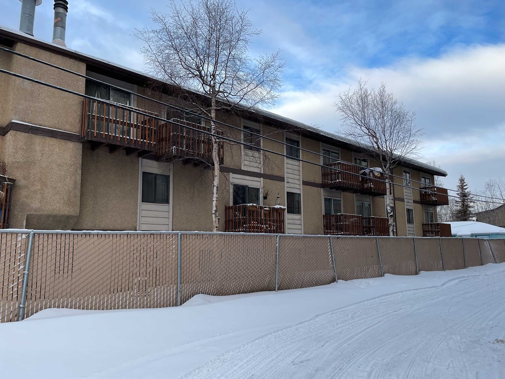 an apartment building with a fence in the snow