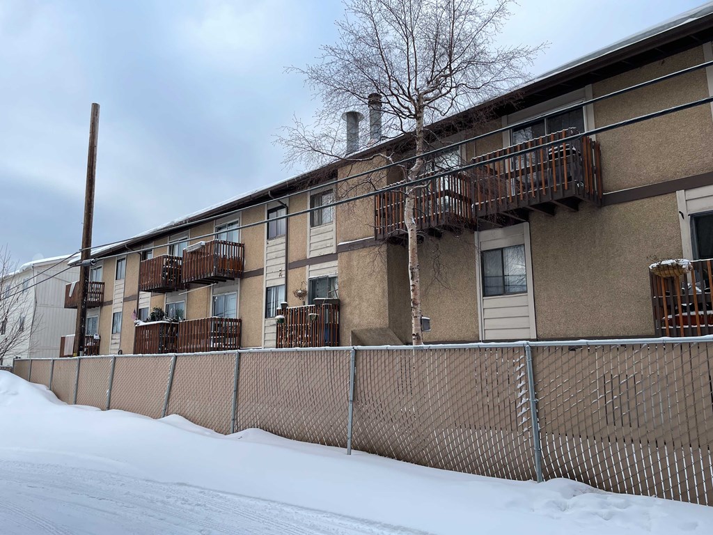 an apartment building with a fence in the snow