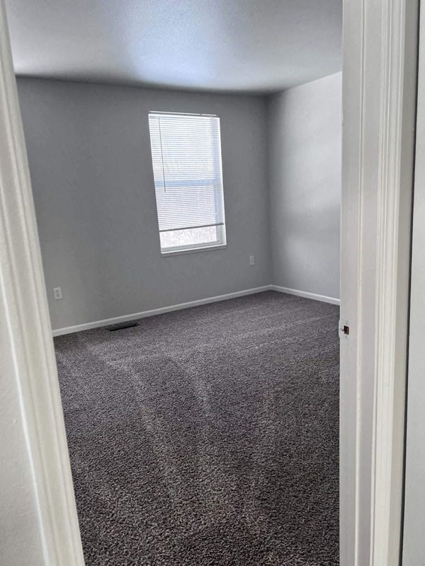 an empty room with gray carpet and a window