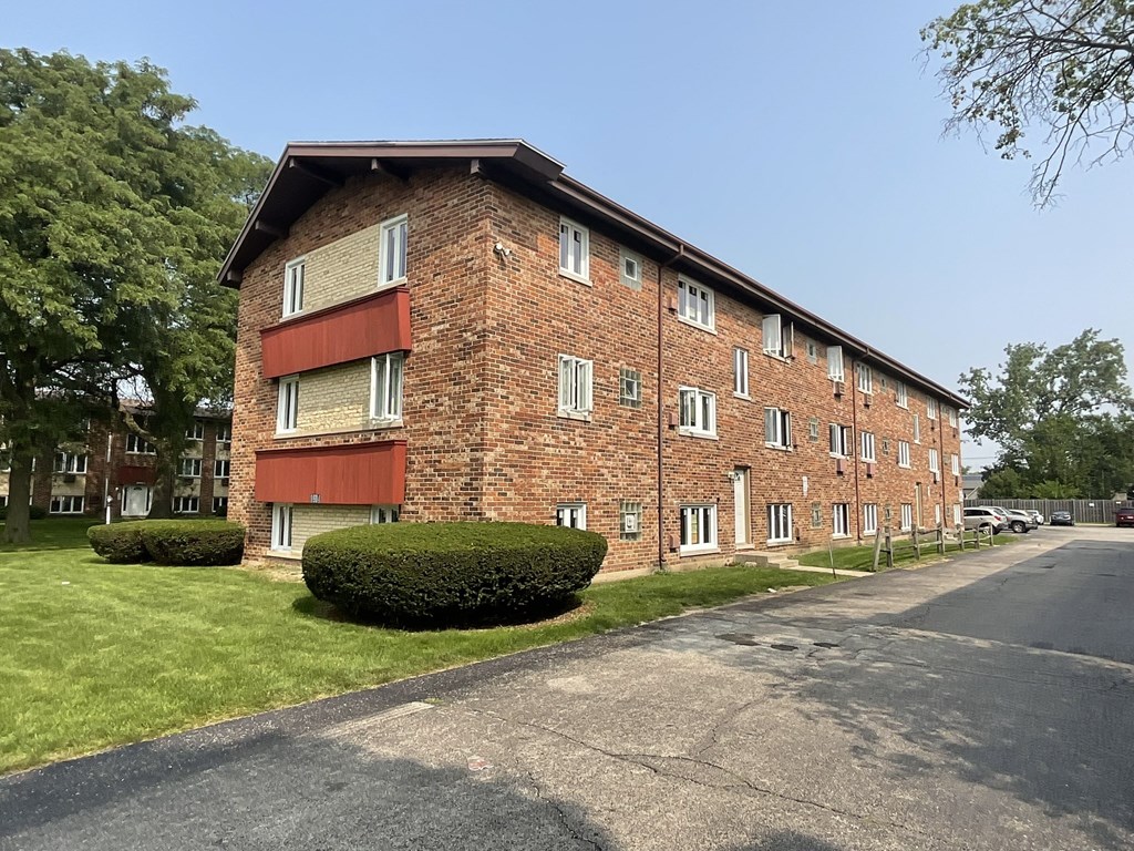 A red brick apartment building with a green lawn in front.at The Countryside, Illinois, 60525?