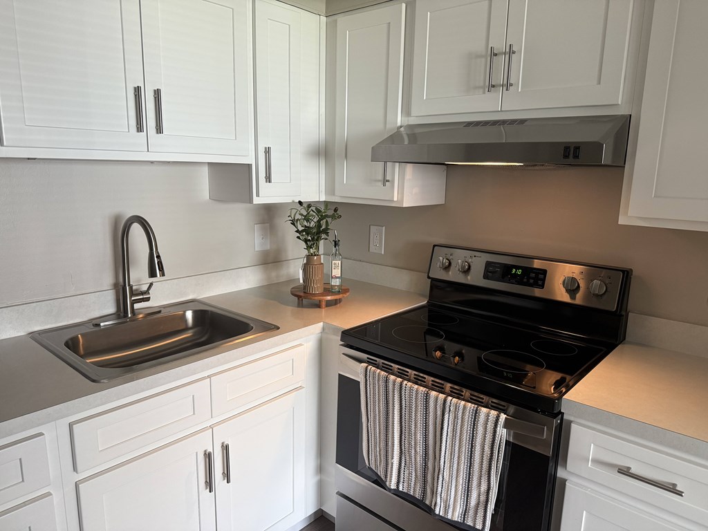 A modern kitchen with white cabinets and a black stove.