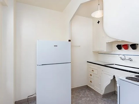 A white refrigerator is in a kitchen with a black counter top.