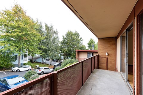 Balcony view with a brown railing overlooks a parking lot and trees at Julie Ann, Portland, OR, 97215
