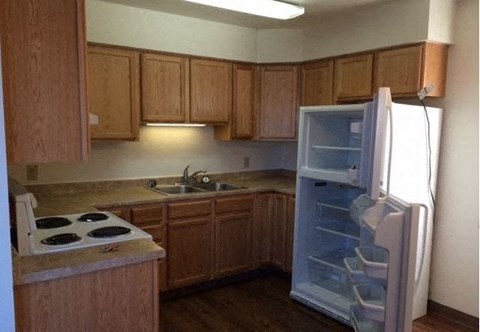 an empty kitchen with an open refrigerator at Woodridge Apartments, Alaska