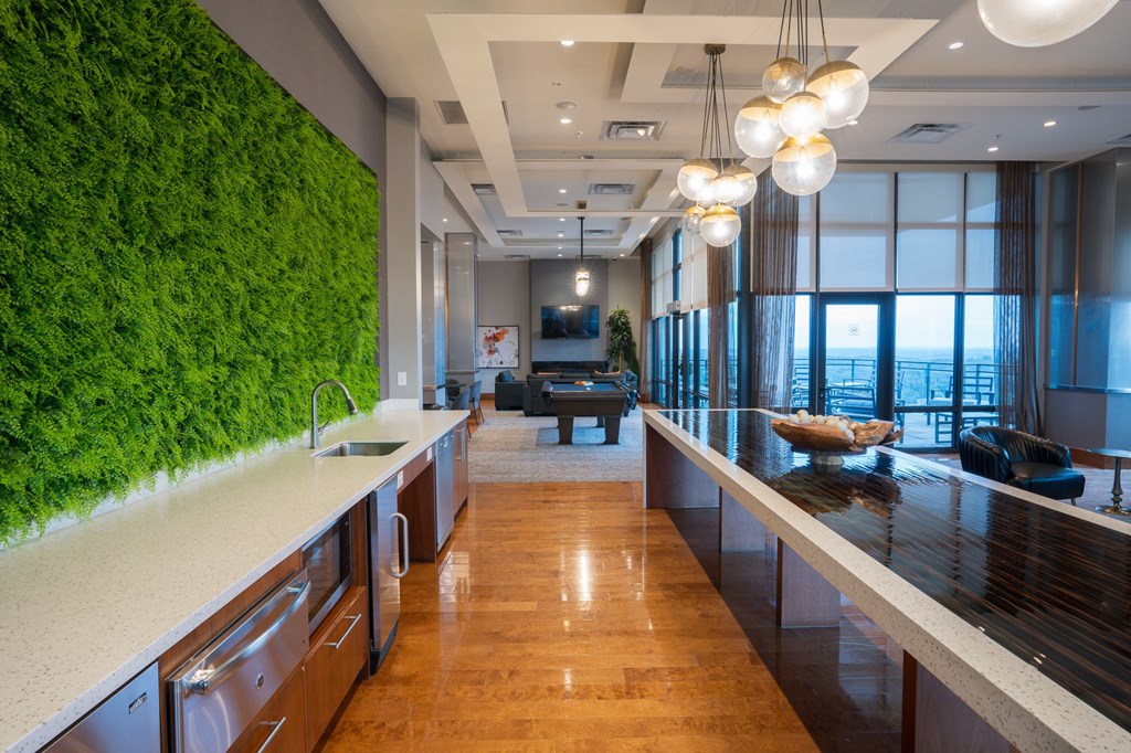 A modern kitchen with a green wall and wooden floors.