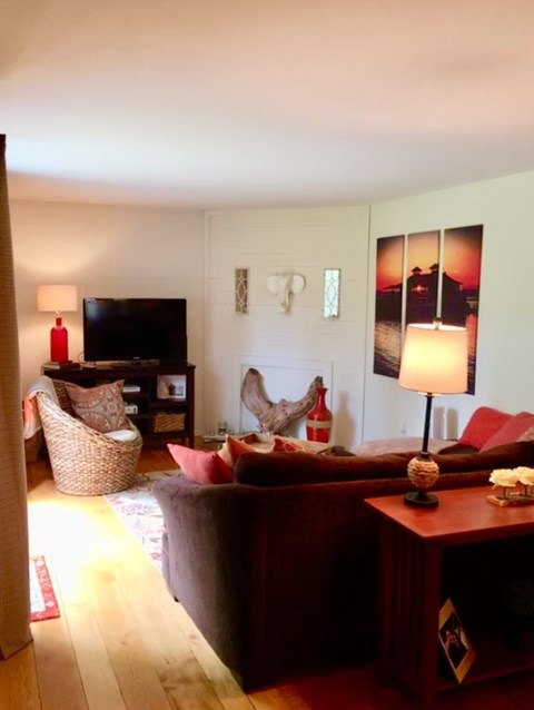 A living room with a red couch and a wooden floor.