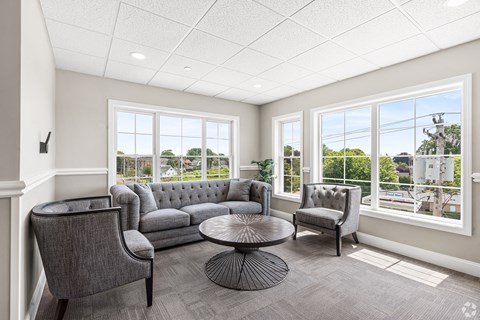 a living room with couches and chairs and large windows