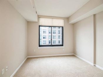 A room with a window and a carpeted floor.