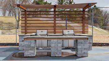 A wooden picnic table with stone pillars and a grill on top.