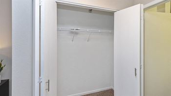 A white closet with a coat hanger is open.
