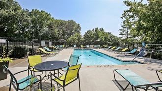 a swimming pool with chairs and tables around it