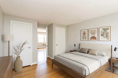 A bedroom with a bed, nightstand, and a vase on a wooden table.