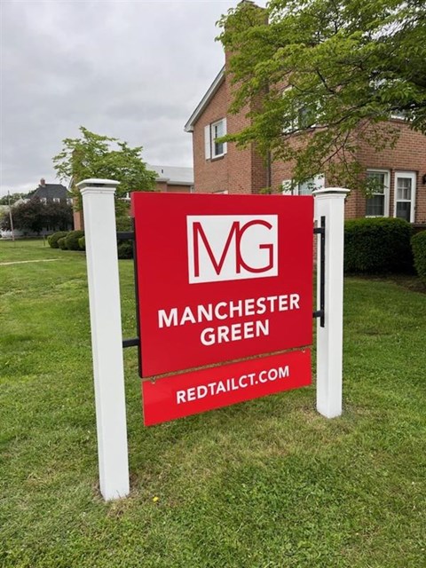 A sign for Manchester Green in front of a building.