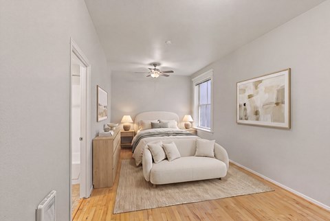 A bedroom with a bed, a couch, and a painting on the wall.