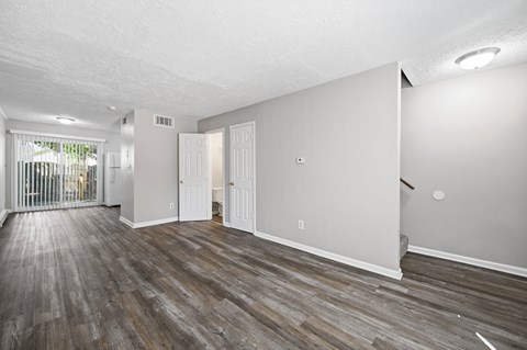 A spacious room with wooden flooring and white walls.