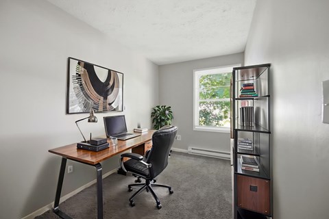 A room with a desk, chair, and bookshelf.