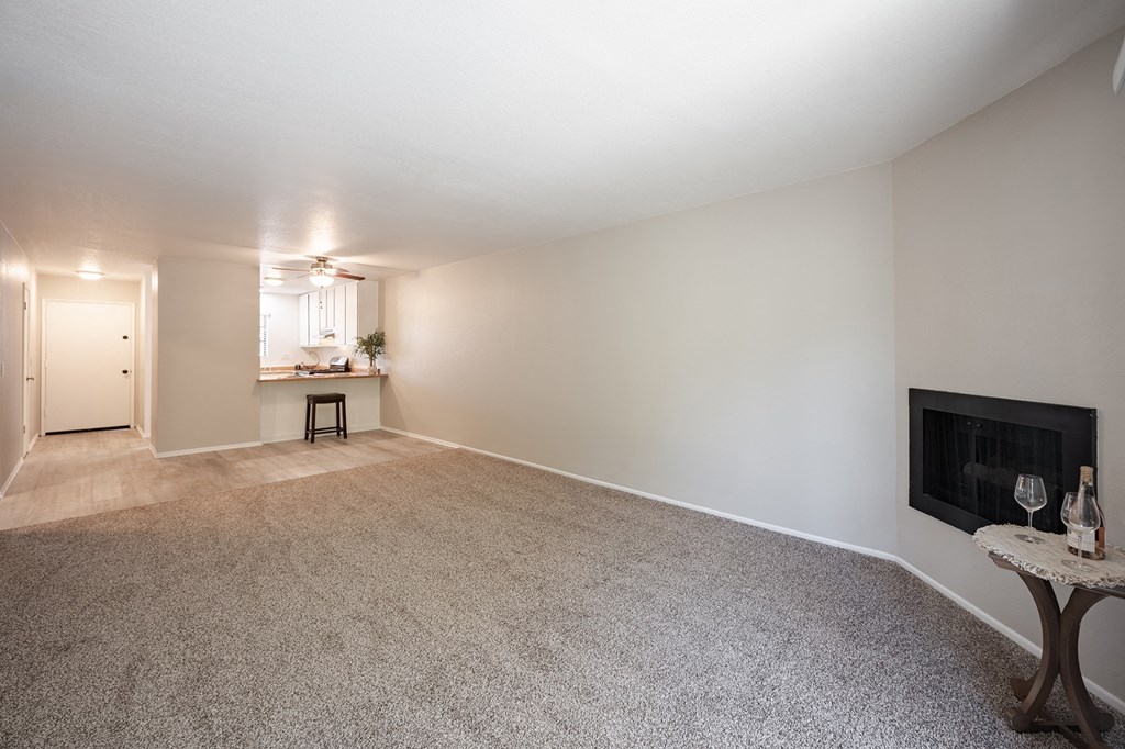 an empty living room with a fireplace and a kitchen at Oak Park Apartments, Solvang, CA 