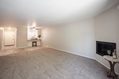 an empty living room with a fireplace and a kitchen at Oak Park Apartments, Solvang, CA