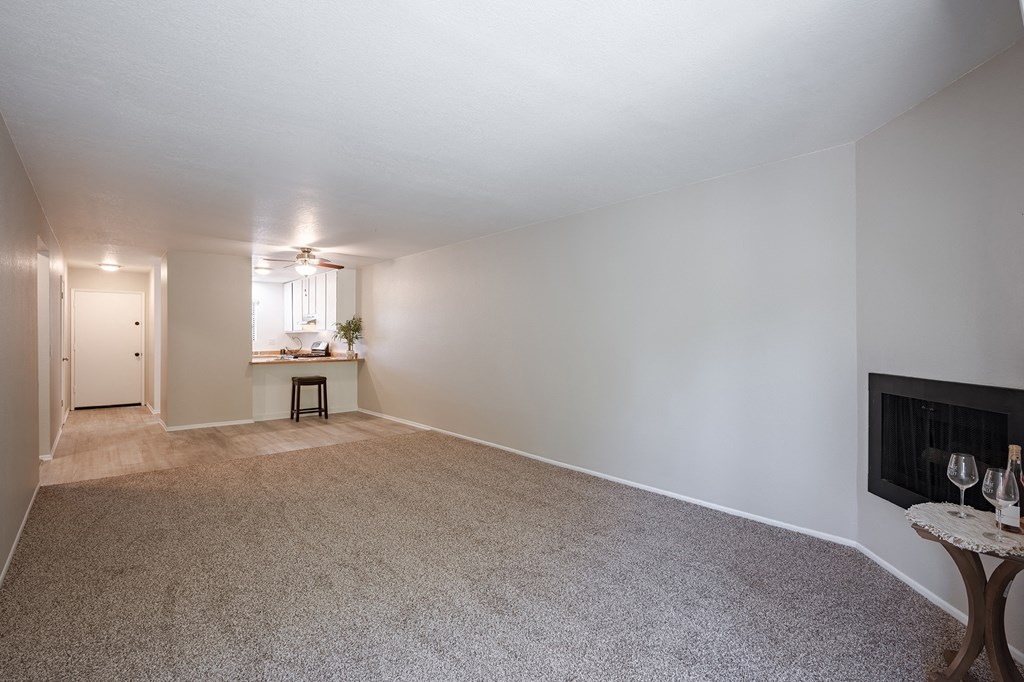 an empty living room with a fireplace and a kitchen  at Oak Park Apartments, California