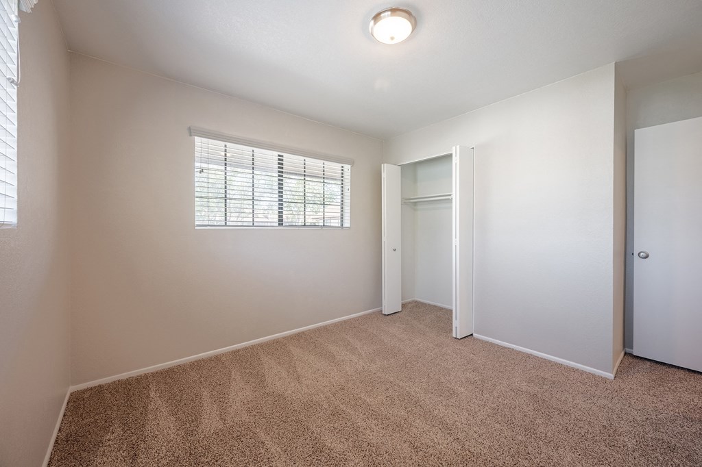 an empty bedroom with a window and a door to a closet  at Oak Park Apartments, California