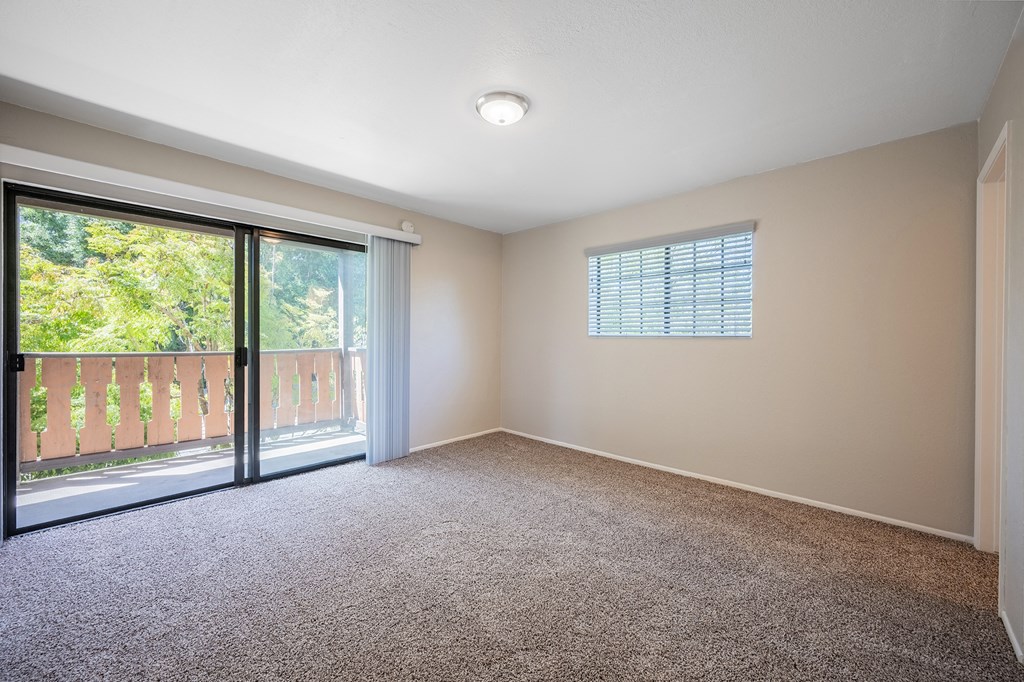 an empty living room with a sliding glass door to a balcony at Oak Park Apartments, Solvang, CA