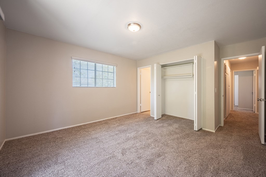 an empty bedroom with carpet and a door to a closet  at Oak Park Apartments, California, 93463