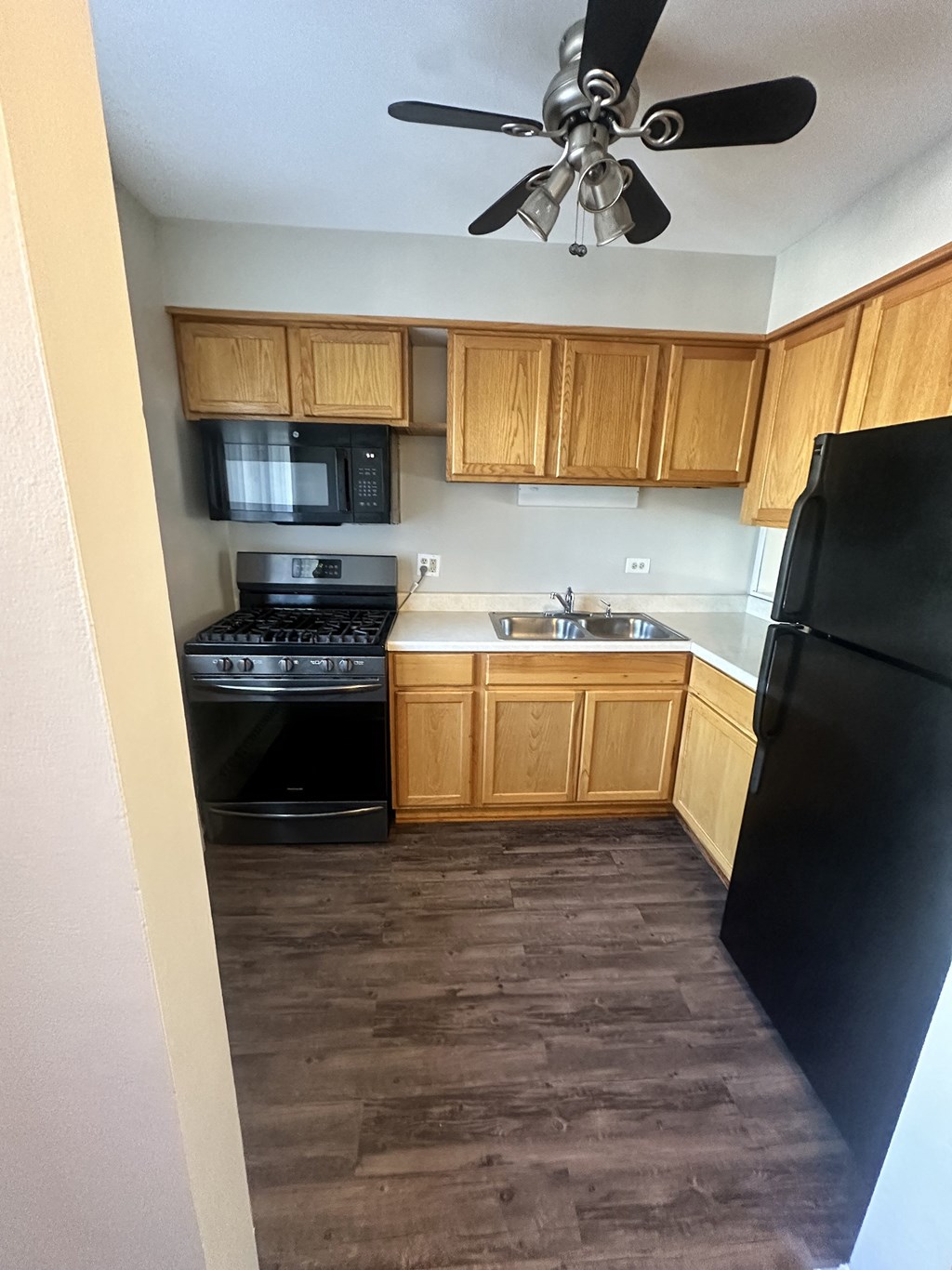 a kitchen with wooden cabinets and black appliances and a ceiling fan at River Oaks, North Aurora, Illinois