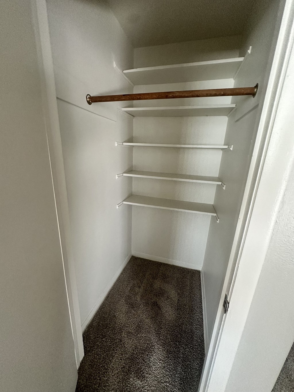 a walk in closet with white shelves and a rail at River Oaks, North Aurora, 60542