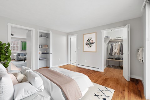 A bedroom with a bed, a couch, a wardrobe, and a plant.