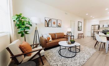 a living room with a couch coffee table and a kitchen in the background