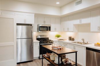 a kitchen with white cabinets and stainless steel appliances