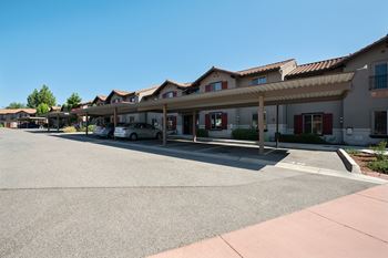 an empty parking lot in front of a hotel with cars parked in front