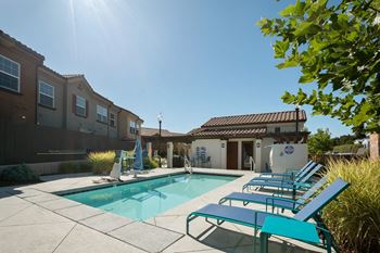a swimming pool with blue chairs next to a house