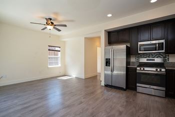an empty kitchen with stainless steel appliances and a ceiling fan