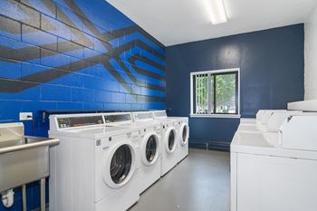 a laundry room with washers and dryers and a blue wall with a window