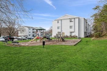 a playground with a swing set in the middle of a grassy area
