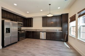 an empty kitchen with dark wood cabinets and stainless steel appliances