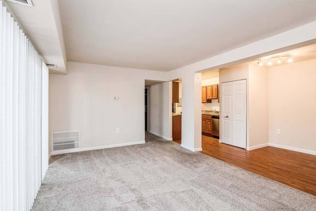 a living room with a white door and a kitchen in the background at ReNew Odenton, Odenton, 21113