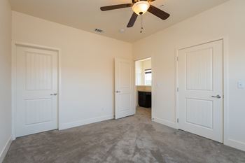 a bedroom with two doors and a ceiling fan