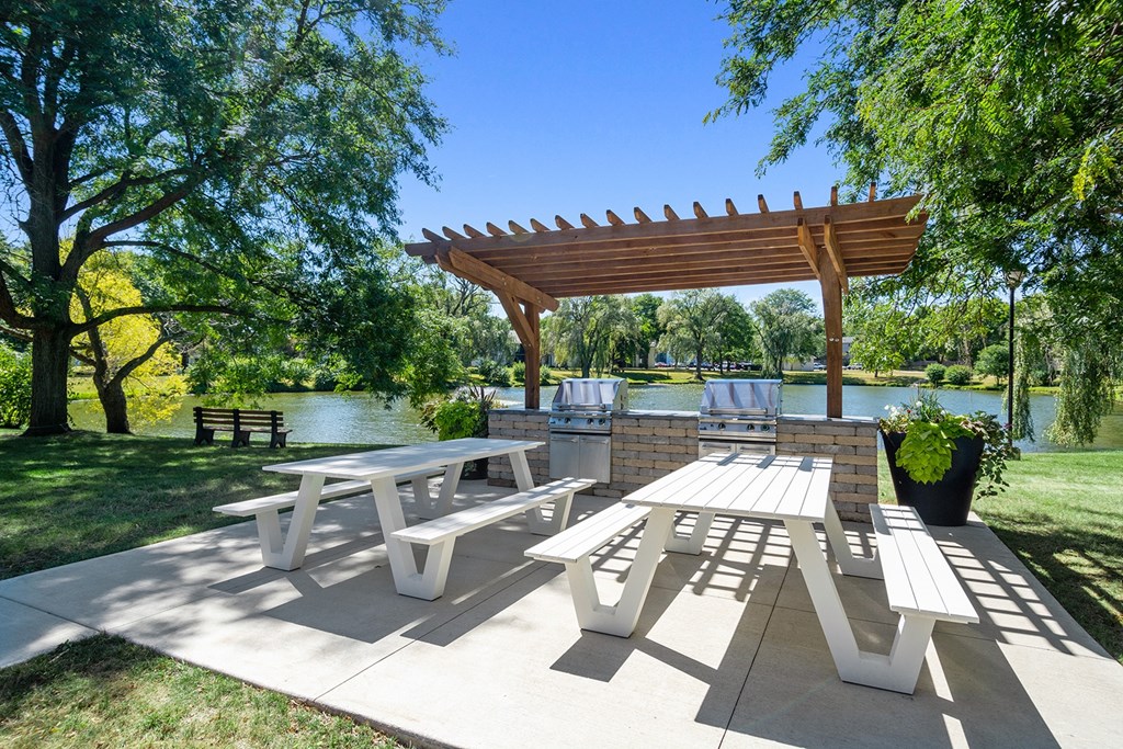A wooden pergola shades a picnic table in a park.