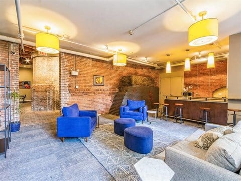 a living room with blue chairs and a brick wall
