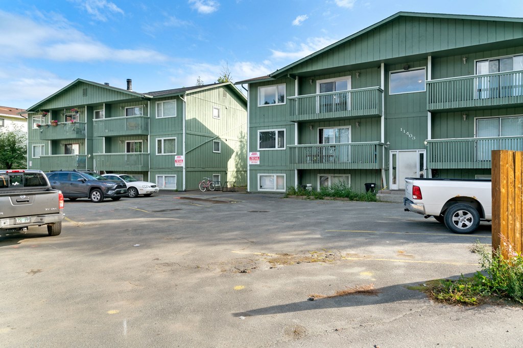 a parking lot in front of a green apartment building  at ReNew Eagle River, Eagle River, AK, 99577