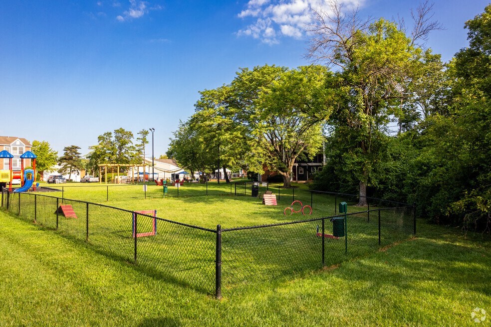 a fenced in park with a playground and trees