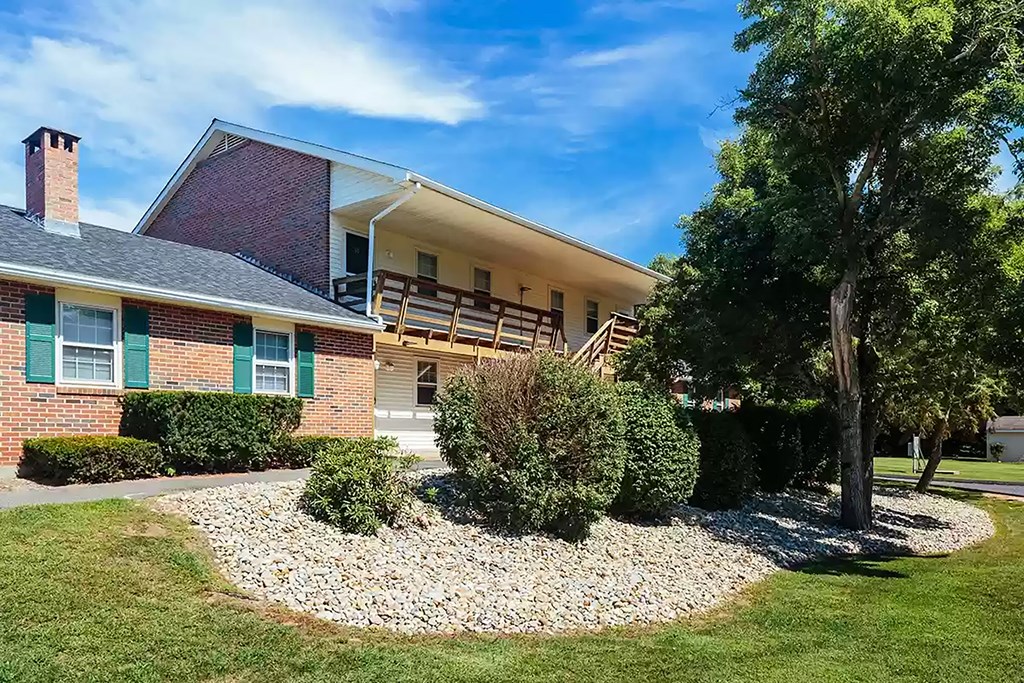 the front of a house with a gravel driveway and trees