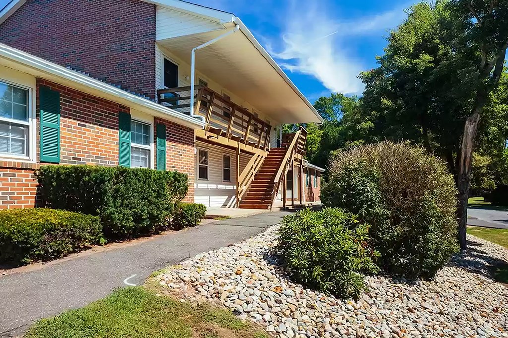 the front of a brick building with stairs and a sidewalk