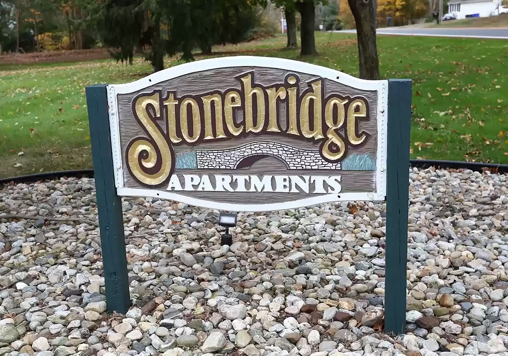 a sign for stonebridge apartments in a park