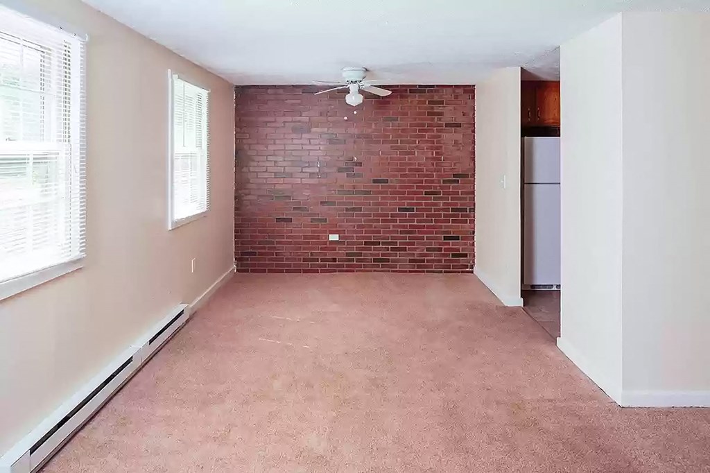 an empty room with a brick wall and a ceiling fan