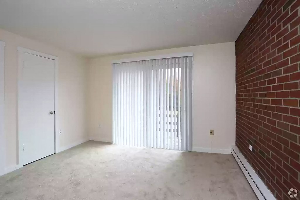an empty living room with a brick wall and a sliding glass door