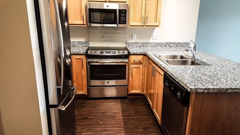 A kitchen with a stainless steel refrigerator and wooden cabinets.